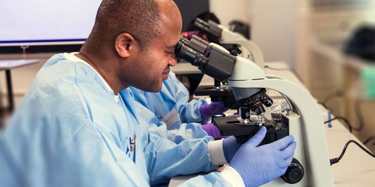 AACC health science student using a microscope.